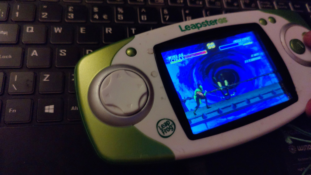 Green and white handheld with Mortal Kombat game in progress