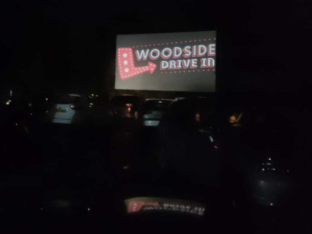 Outdoor cinema screen and parked cars in the dark